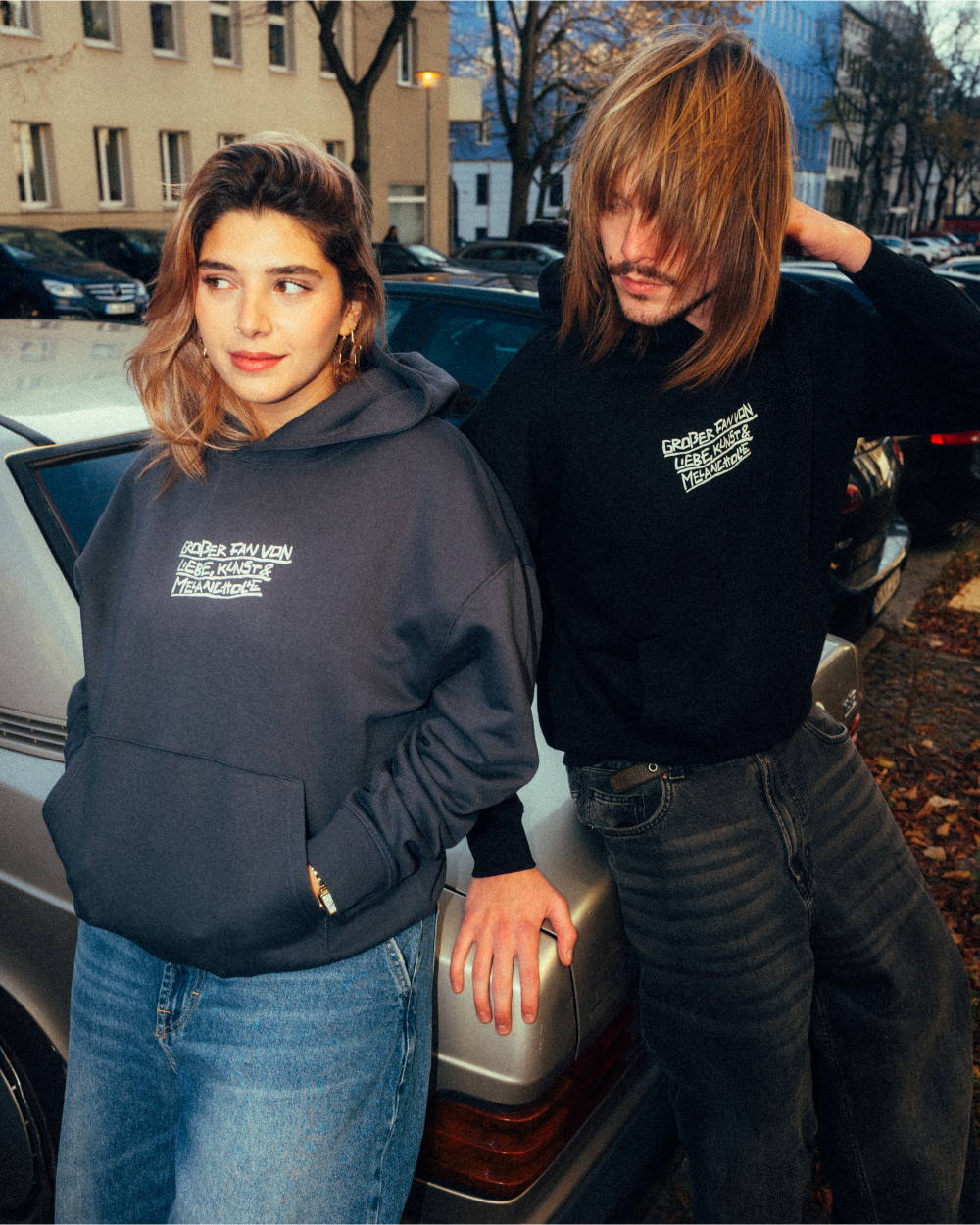 Schwarzer Hoodie aus Baumwollmischung mit weißem Frontprint in handschriftlicher Optik. Der mittig platzierte Schriftzug lautet: „GRÖßER FAN VON LIEBE, KÜSSTEN UND MENSCHEN“. Der Kapuzenpullover hat eine große Kängurutasche, Rippbündchen an Ärmeln und Saum sowie eine lässige, leicht oversized geschnittene Passform.