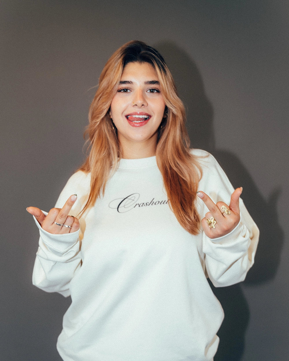 Cremeweißer Sweatshirt aus weichem Baumwollstoff mit schwarzem, fein geschwungenem Schriftzug „Crashout“ mittig auf der Brust. Der Pullover hat einen Rundhalsausschnitt, lange Ärmel und gerippte Bündchen an Ärmeln und Saum. Die Passform ist locker und komfortabel.